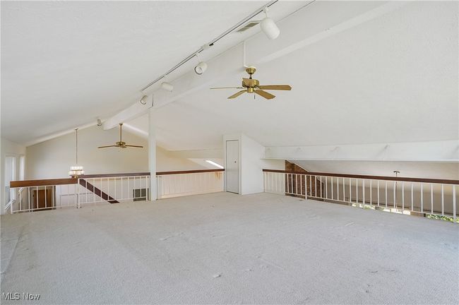 Bonus room featuring ceiling fan with notable chandelier, vaulted ceiling with beams, and carpet | Image 25