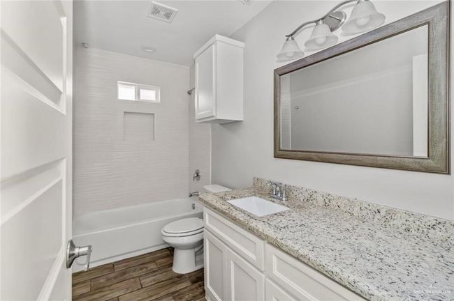 Full bath with vanity, toilet, wood finished floors, and tub / shower combination | Image 9