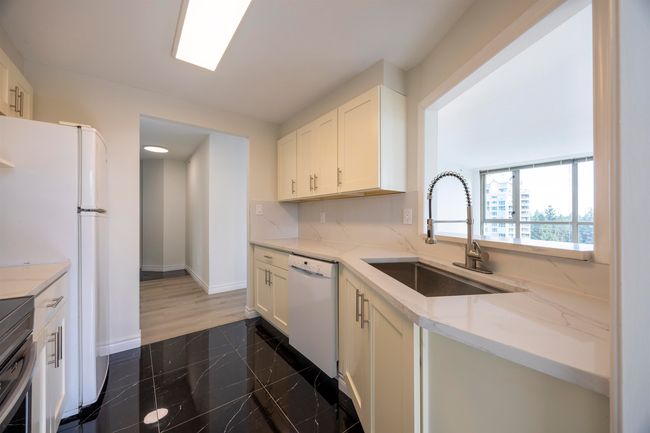 Kitchen with white dishwasher, granite tiled floors, light stone counters, white cabinets, and range | Image 4