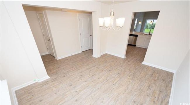 Spare room featuring an inviting chandelier, baseboards, and light wood finished floors | Image 6