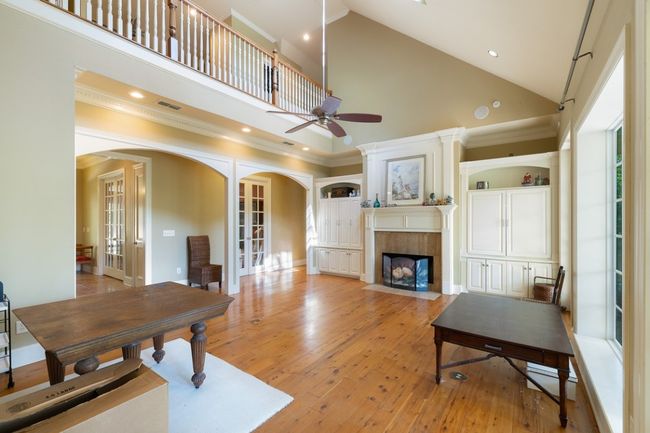 Living room with light wood-style flooring, arched walkways, a tiled fireplace, a ceiling fan, and high vaulted ceiling | Image 13