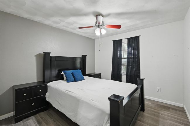 Bedroom with dark wood-style flooring, baseboards, and a ceiling fan | Image 15
