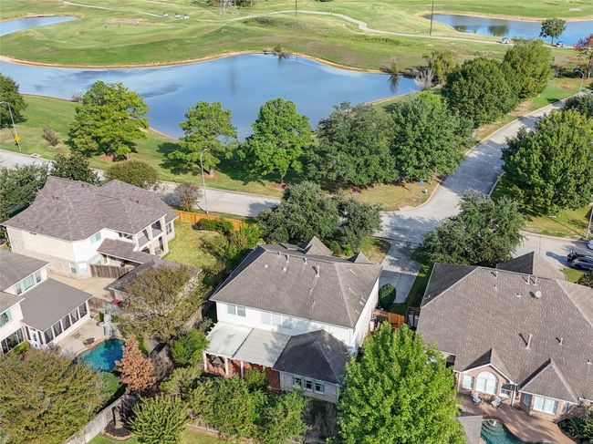 Surrounded by spacious homes featuring landscaped yards. The properties faces onto a scenic golf course with a pond, offering a picturesque view. The area is lush with greenery, providing a serene and attractive setting for potential home buyers. | Image 33