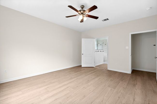 Unfurnished bedroom with light wood finished floors, ensuite bath, and a ceiling fan | Image 29