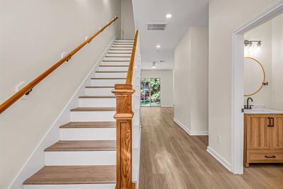 First floor entry way with powder room to the right, stained wood accents on the stairway and main living space beyond. | Image 3