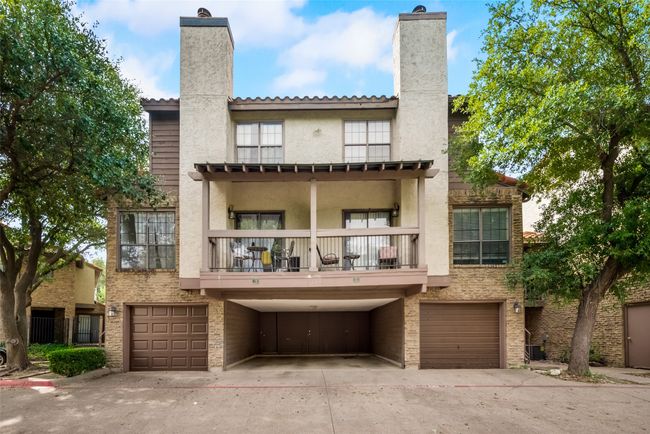 Back of house featuring a chimney, an attached garage, a balcony, and driveway | Image 17