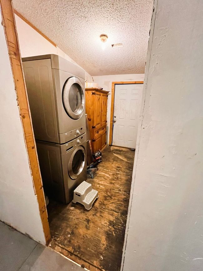 Laundry room featuring estacked washer and dryer and a textured ceiling | Image 5