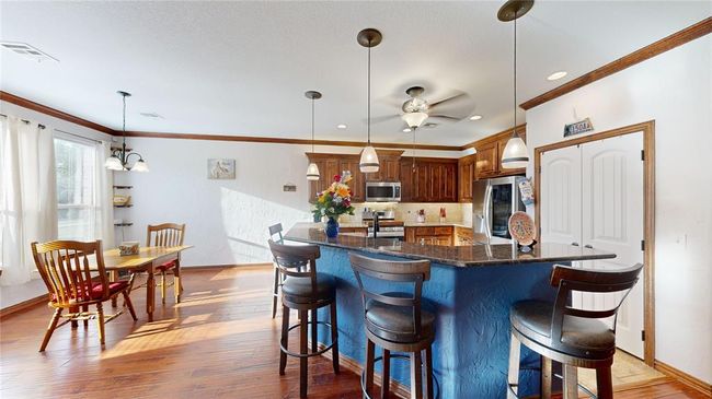 Kitchen with stainless steel appliances, a kitchen breakfast bar, baseboards, and crown molding | Image 15