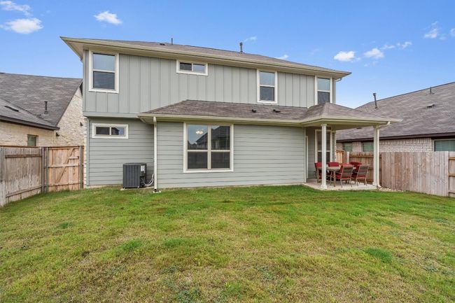 Back of house with board and batten siding, a patio area, central AC, and a gate | Image 34