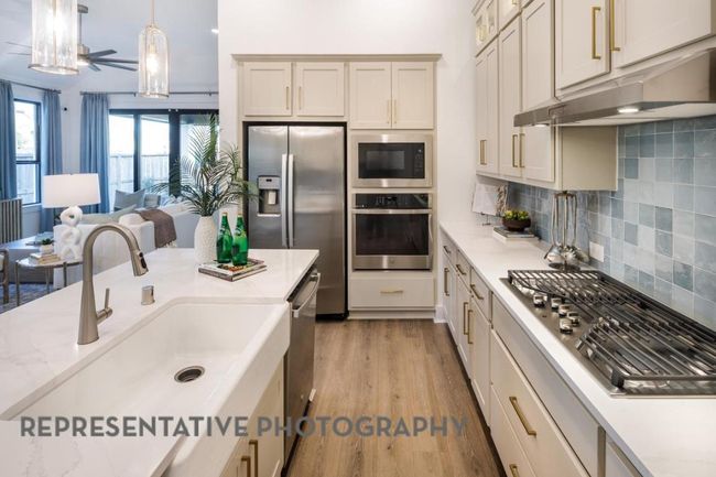 Kitchen featuring appliances with stainless steel finishes, under cabinet range hood, light wood-style floors, open floor plan, and tasteful backsplash | Image 4