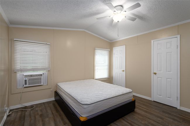 Bedroom featuring dark wood finished floors, lofted ceiling, cooling unit, a textured ceiling, and ornamental molding | Image 18