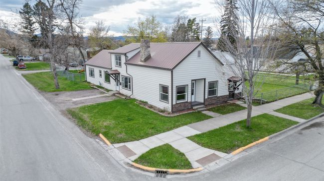 View of front of home featuring fence, a front lawn, driveway, stone siding, and metal roof | Image 35