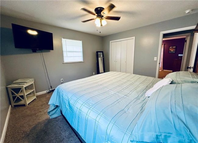 Bedroom with dark colored carpet, baseboards, a closet, and a ceiling fan | Image 14