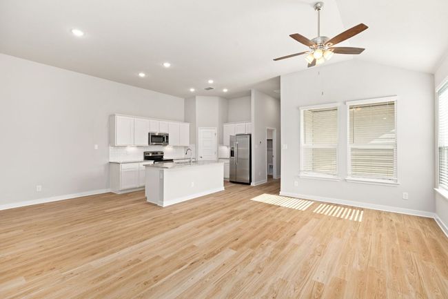 Kitchen featuring white cabinets, open floor plan, a kitchen island with sink, stainless steel appliances, and light wood-type flooring | Image 10