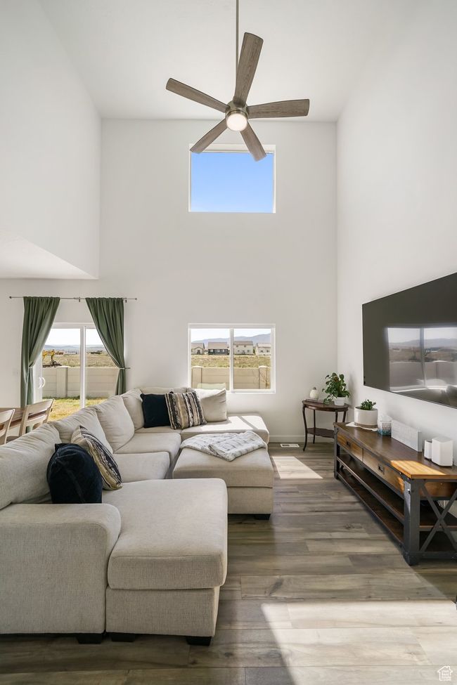 Living room with a high ceiling, ceiling fan, and wood finished floors | Image 10