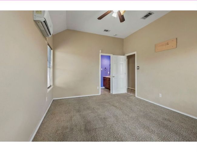 Unfurnished bedroom featuring vaulted ceiling, carpet, a wall unit AC, ceiling fan, and connected bathroom | Image 23