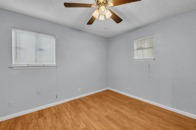 Empty room featuring a textured ceiling, baseboards, and light wood-style floors | Image 12