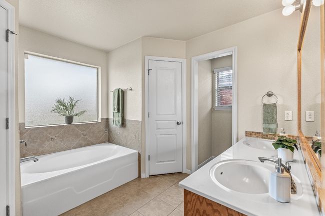 Bathroom with double vanity, tile patterned flooring, and a garden tub | Image 10