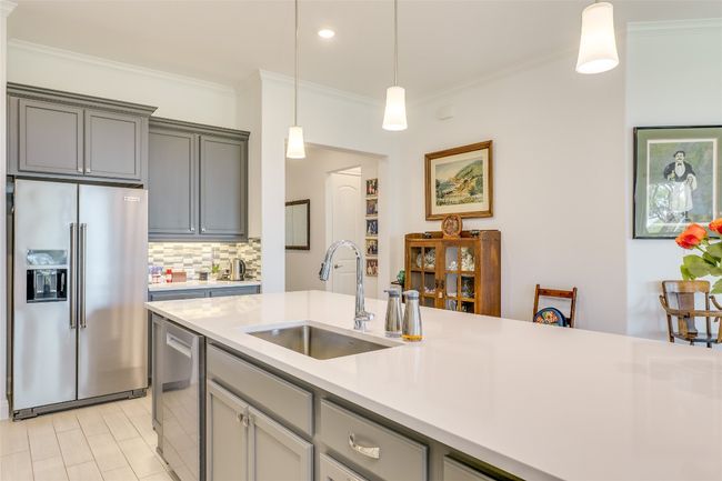 Kitchen featuring gray cabinetry, stainless steel appliances, ornamental molding, pendant lighting, and decorative backsplash | Image 5