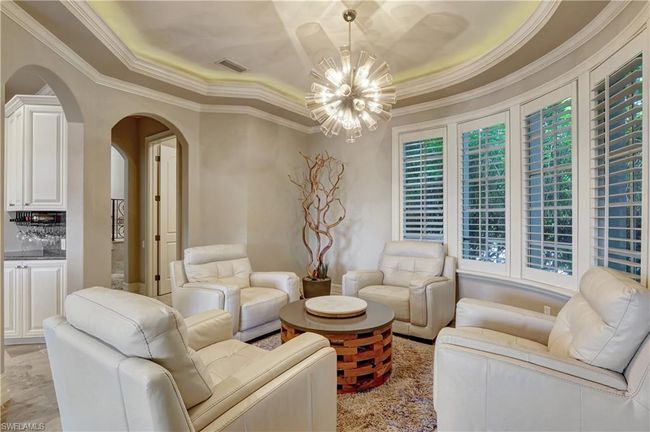 Living room with a notable chandelier, a raised ceiling, crown molding, visible vents, and arched walkways | Image 23