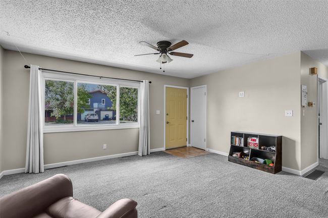 Living area with carpet, a ceiling fan, a textured ceiling, and baseboards | Image 5