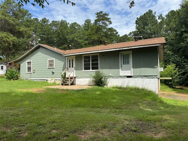 Rear view of property featuring entry steps, a lawn, and a shingled roof | Image 18