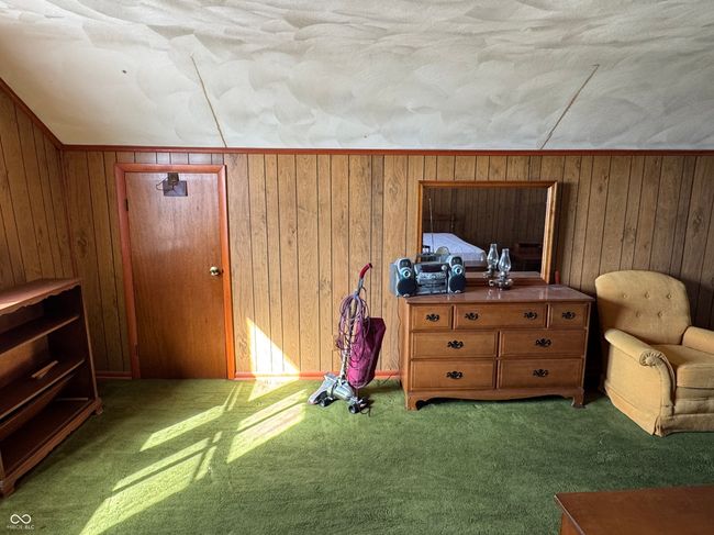 unfurnished bedroom with wood walls, vaulted ceiling, and carpet | Image 28