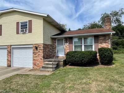 Tri-level home with cooling unit, a garage, and a front yard | Image 2