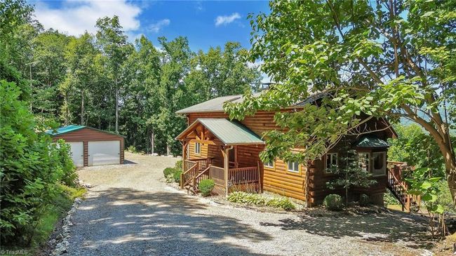 Step into the charming allure of this rustic cabin, where the front entrance beckons with a welcoming aura, framed by a serene circle drive enveloped in the privacy of two distinct keypad-operated gates. | Image 7