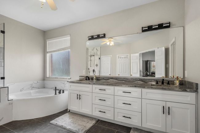Bathroom with a ceiling fan, double vanity, a garden tub, and tile patterned floors | Image 22
