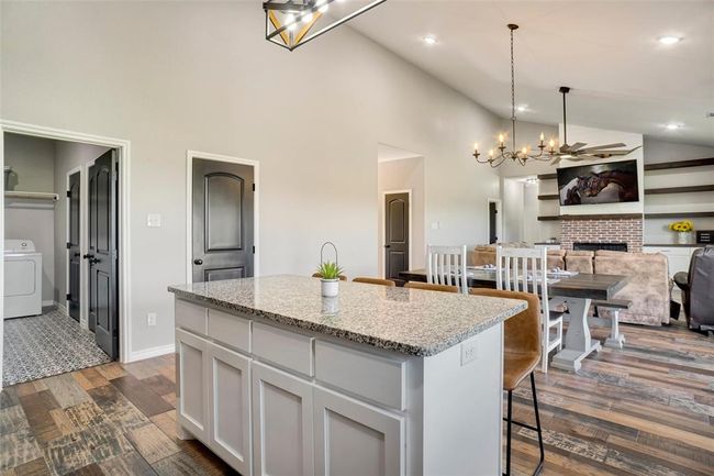 Kitchen with dark hardwood / wood-style floors, a fireplace, a kitchen island, white cabinets, and washer / clothes dryer | Image 16