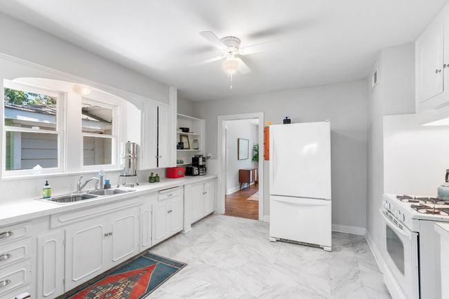 View of kitchen cabinets, refrigerator and range. Doorway leads to bedroom. | Image 15