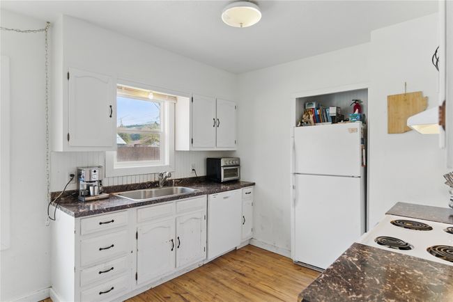 Kitchen with white cabinets, light wood-style flooring, a sink, and white appliances | Image 16
