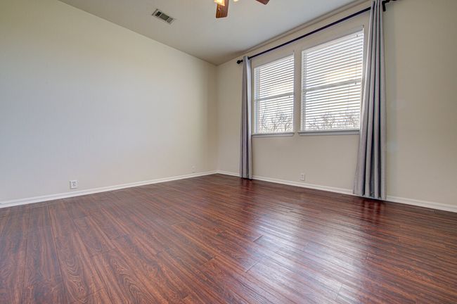Empty room with baseboards, wood finished floors, visible vents, and ceiling fan | Image 24