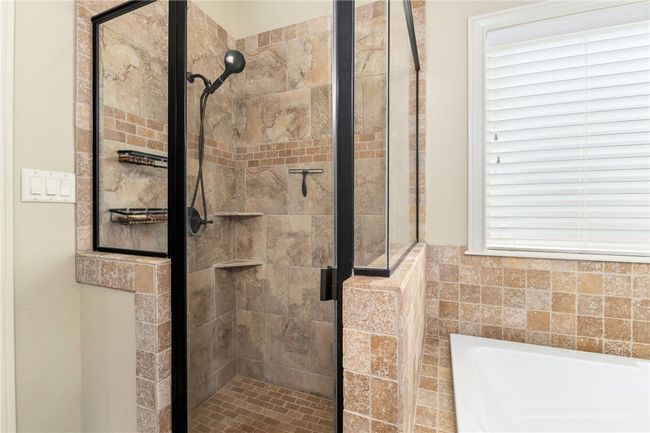 A closer look at the walk-in shower reveals elegant tile surround with a stylish accent tile and rich bronze finishes, adding a touch of luxury to the space. | Image 21