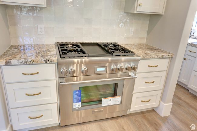 Kitchen featuring stainless steel stove, light wood-style flooring, and white cabinets | Image 10
