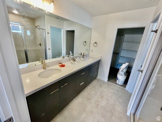 Bathroom featuring a shower stall, double vanity, and a spacious closet | Image 12