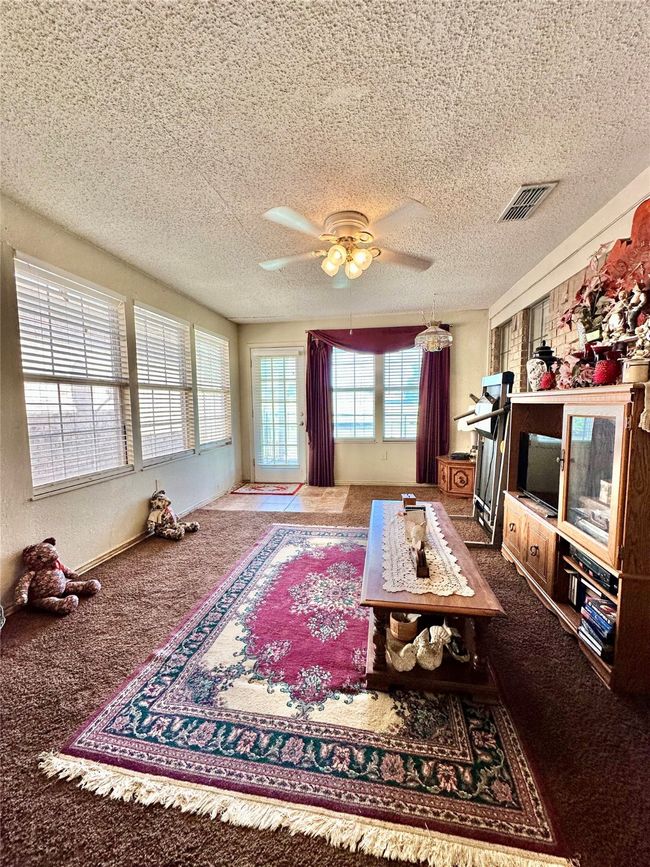 Living area featuring carpet flooring, a ceiling fan, and a textured ceiling | Image 24