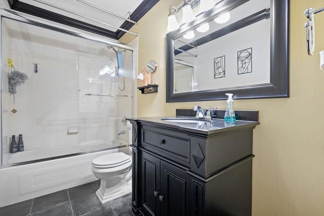 Bathroom with toilet, vanity, shower / bath combination with glass door, and tile patterned floors | Image 25