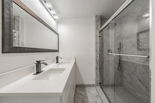 Full bathroom featuring double vanity, a marble finish shower, and marble finish flooring | Image 17