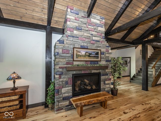 living room with stairway, baseboards, wood finished floors, a fireplace, and wooden ceiling | Image 10