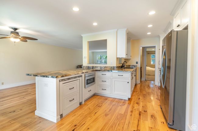 Kitchen with white cabinets, recessed lighting, a sink, freestanding refrigerator, and dark stone counters | Image 7