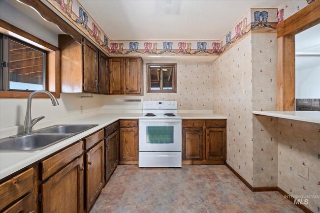Kitchen with white range with electric stovetop, light countertops, and wallpapered walls | Image 12