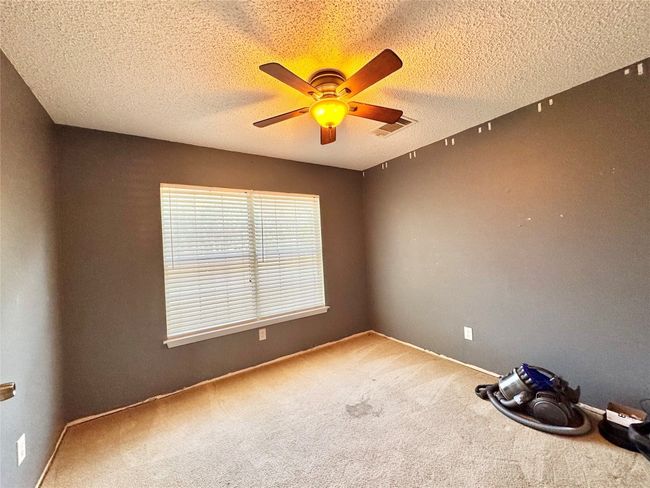 Carpeted empty room with ceiling fan and a textured ceiling | Image 7