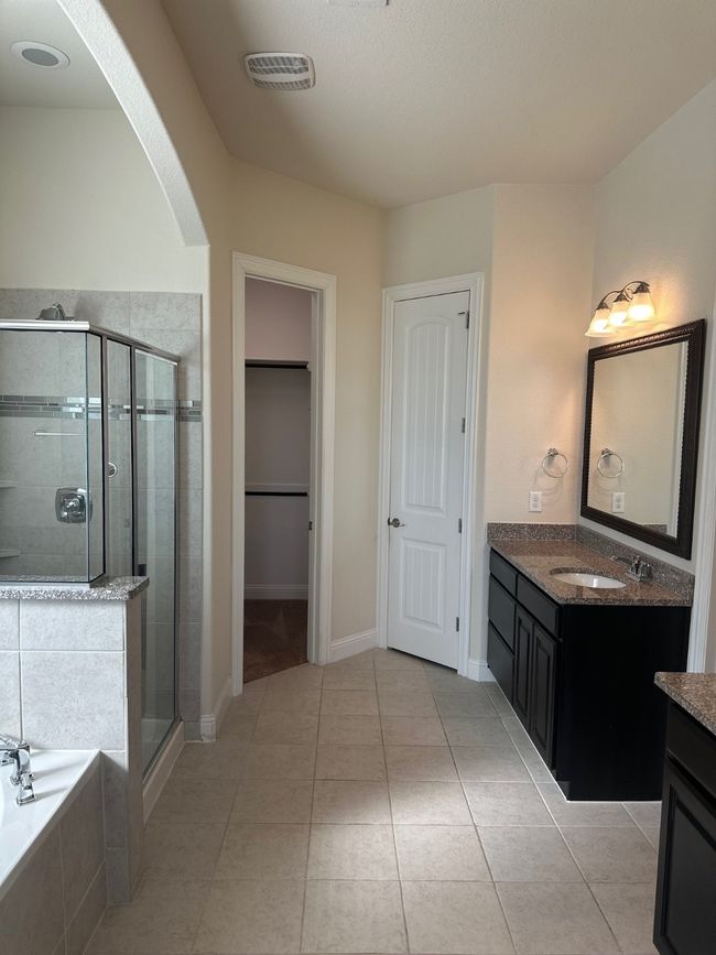 Full bath featuring a walk in closet, visible vents, a stall shower, vanity, and a bath | Image 14