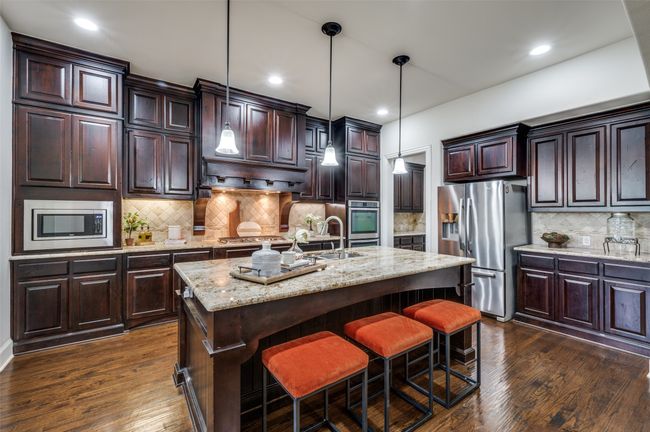 Kitchen with stainless steel appliances, tasteful backsplash, dark wood-type flooring, a center island with sink, and dark brown cabinets | Image 10
