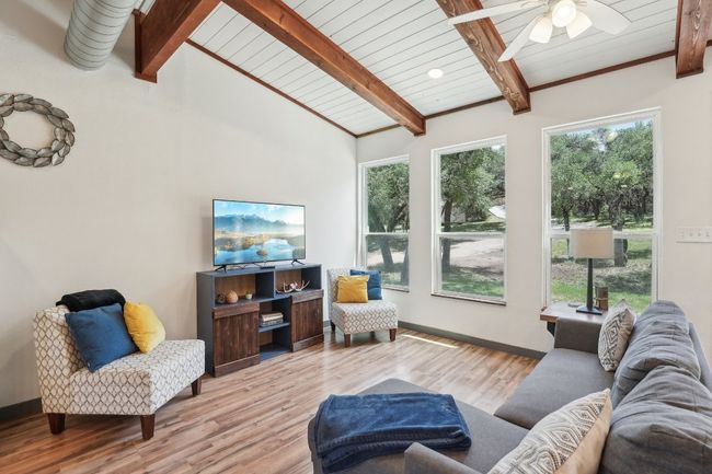 Living room with a ceiling fan, wood finished floors, wood ceiling, and baseboards | Image 6