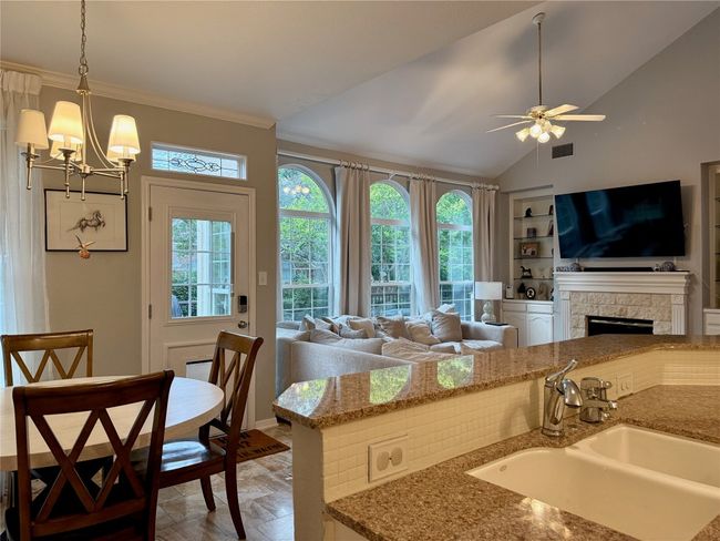 Kitchen with visible vents, open floor plan, built in shelves, a sink, and ceiling fan with notable chandelier | Image 12