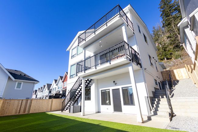 Back of house with stairway, a balcony, a fenced backyard, and a patio | Image 11
