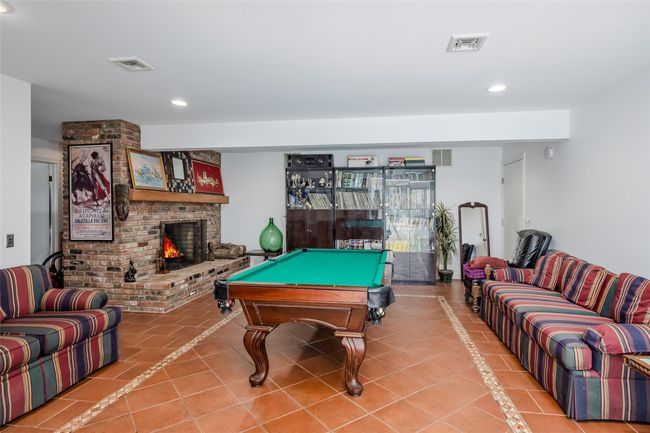 Recreation room with tile patterned flooring, a brick fireplace, and visible vents | Image 30